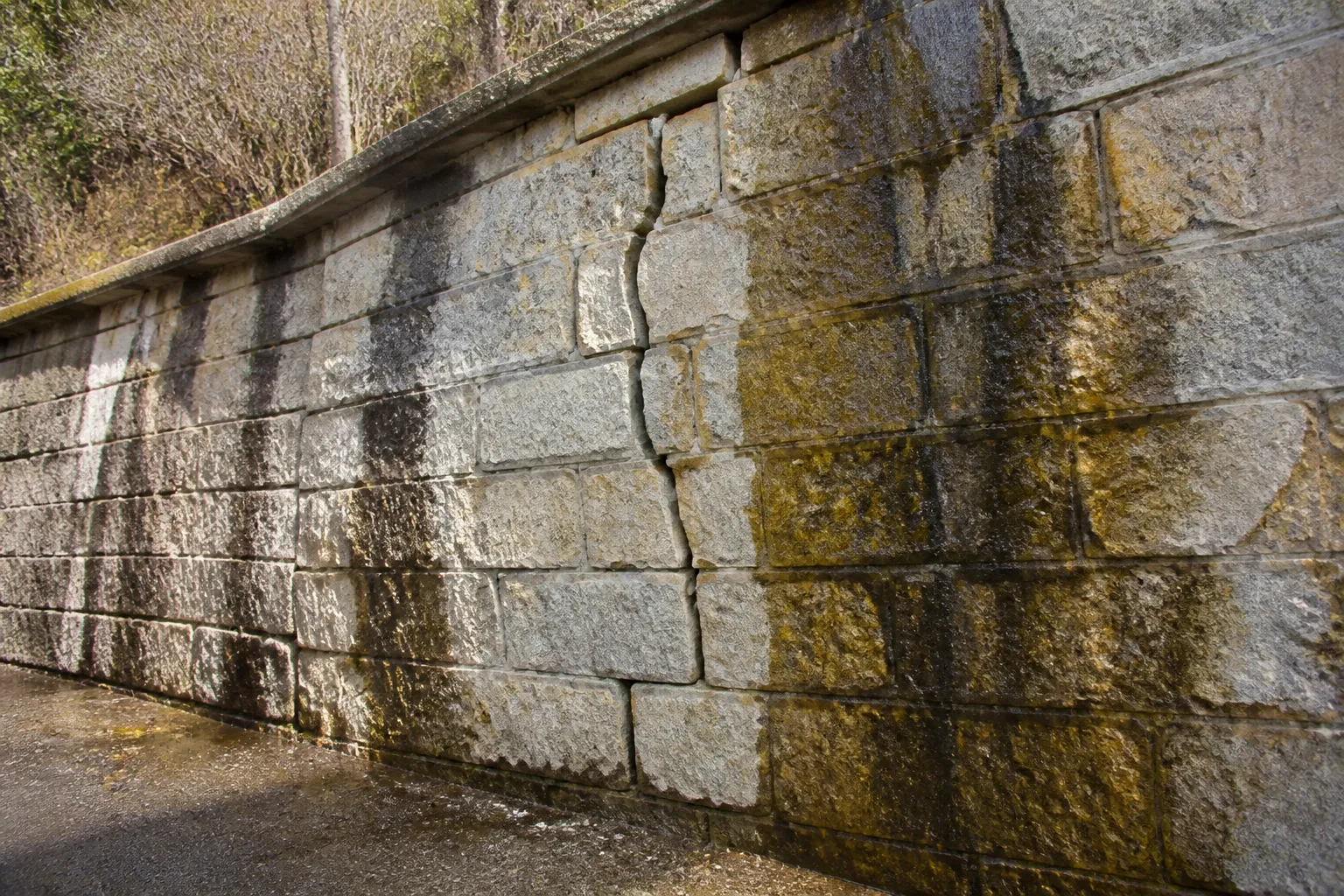 Mur de soutenement ancien en pierre avec une fissure et des traces d ecoulement d eau