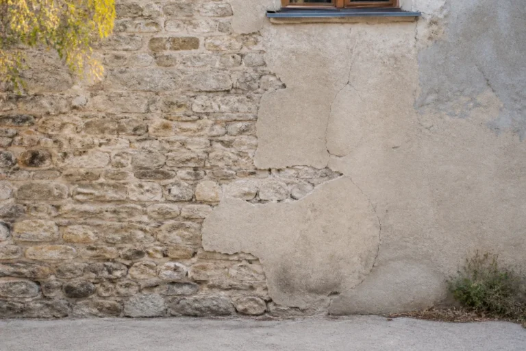 Mur ancien en pierre partiellement recouvert d un enduit ciment fissure dans un village du Rhone