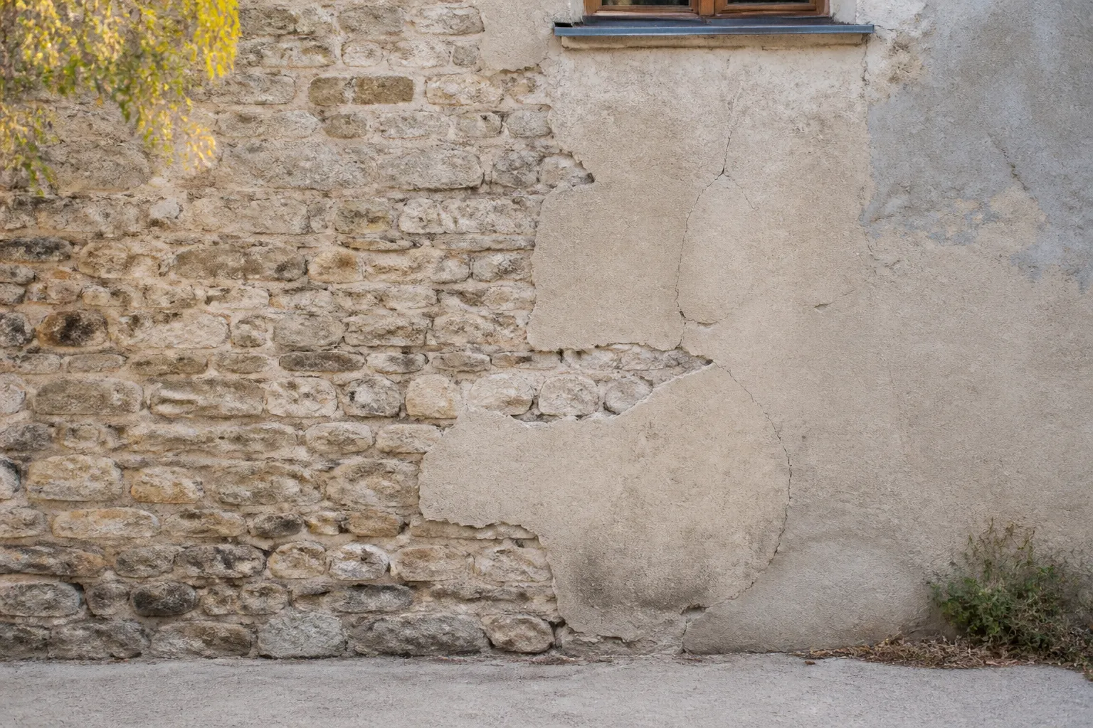 Mur ancien en pierre partiellement recouvert d un enduit ciment fissure dans un village du Rhone