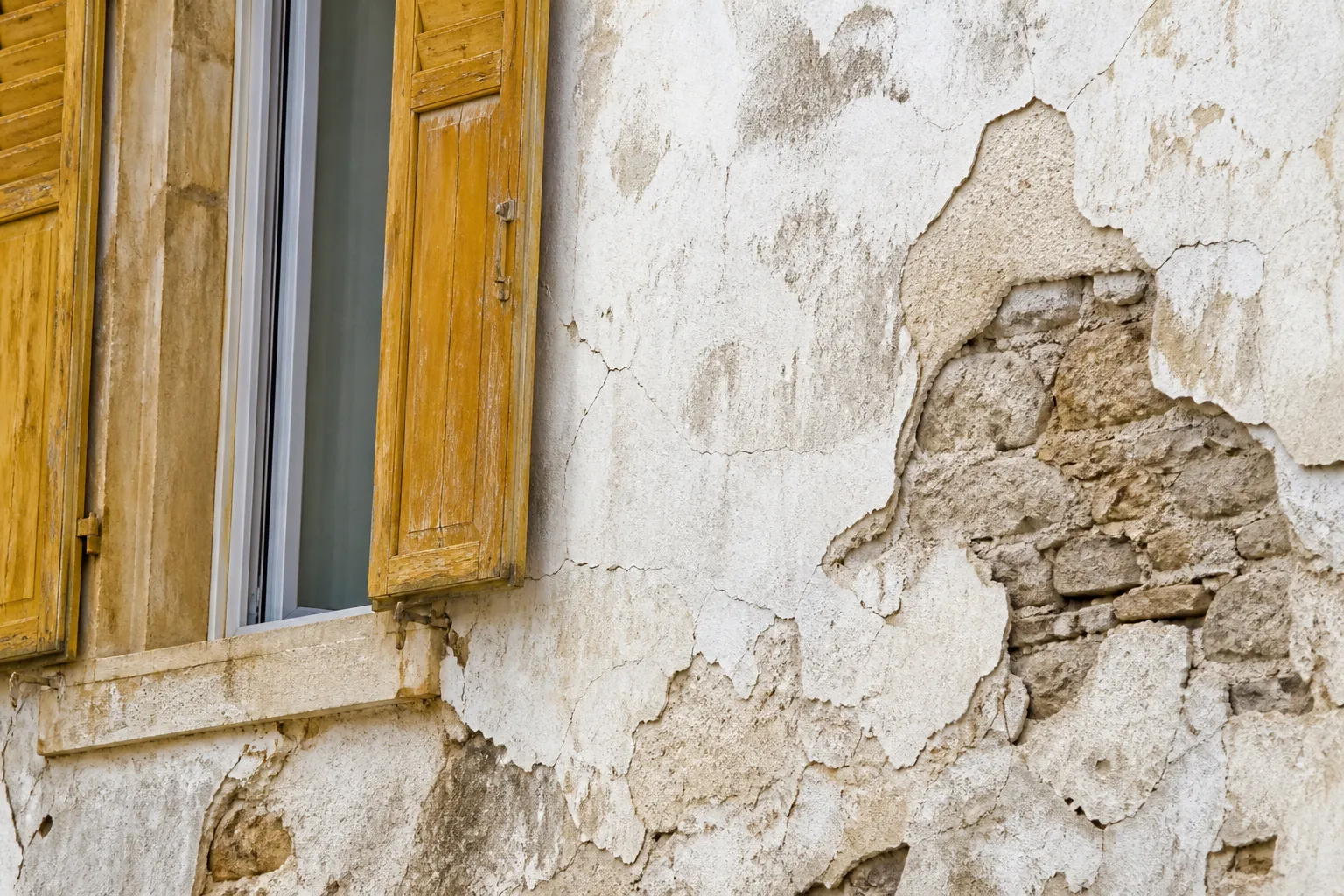 Detail d une facade ancienne enduite a la chaux avec fissures et enduit decolle