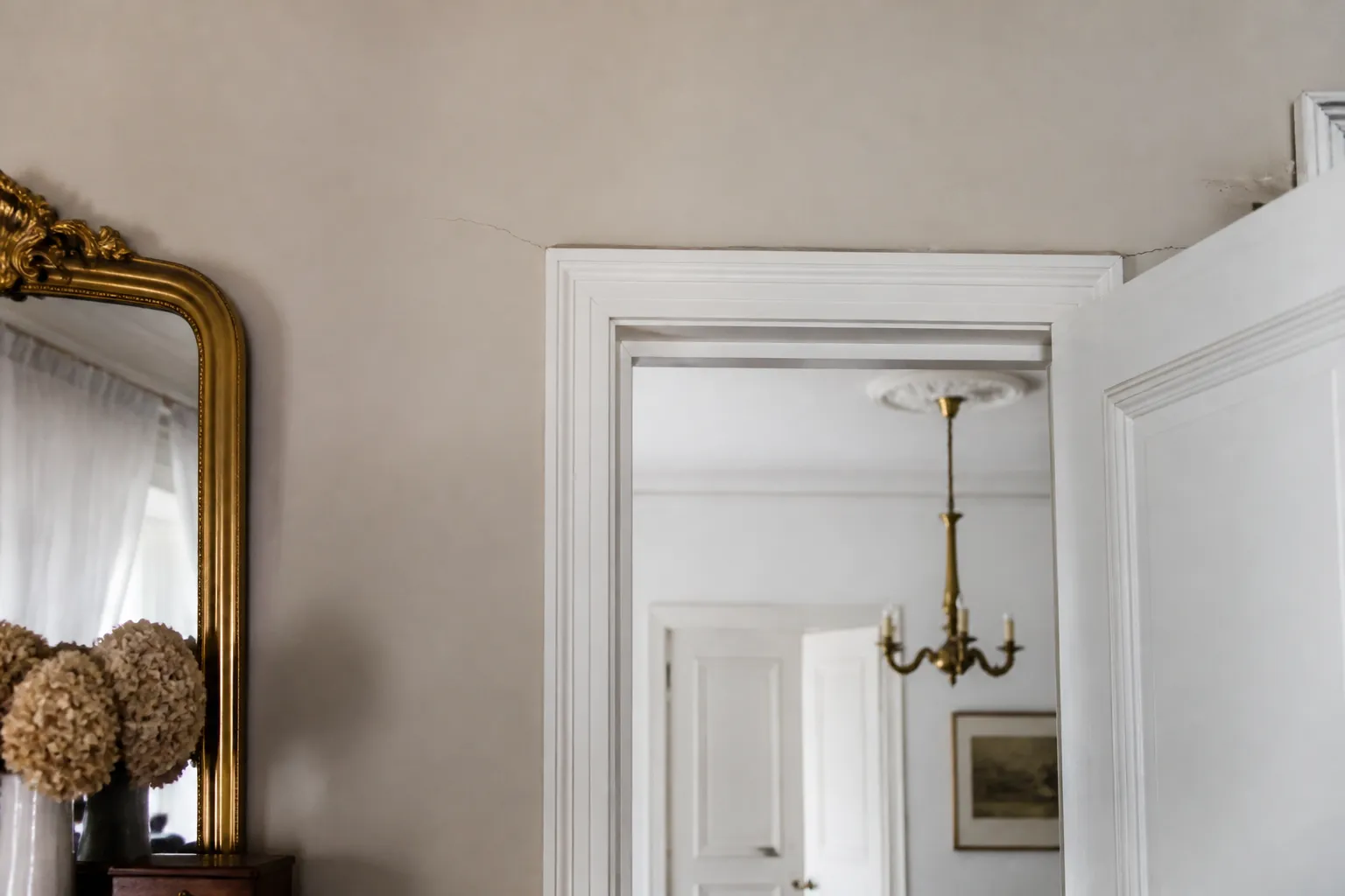 Mur interieur d un appartement ancien avec une fine fissure au dessus d une porte